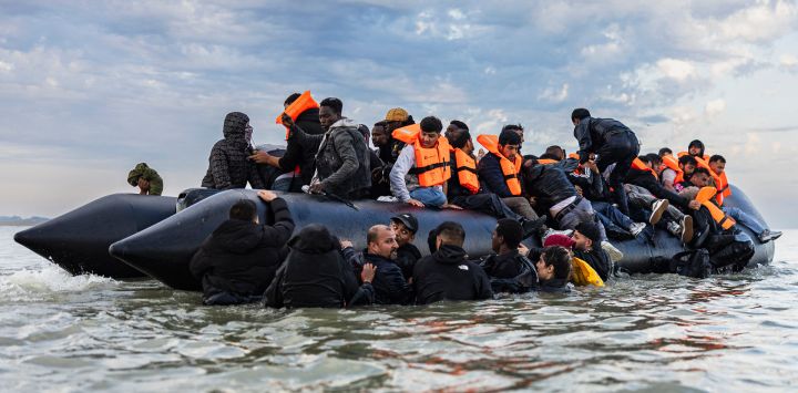 Migrantes intentan subir a un barco de contrabandistas para intentar cruzar el Canal de la Mancha frente a la playa de Gravelines, en el norte de Francia.