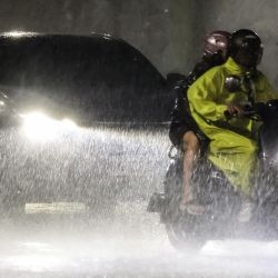 Unas personas viajan en motocicleta bajo las fuertes lluvias provocadas por el tifón Podul en Kaohsiung, Taiwán. | Foto:I-Hwa Cheng / AFP