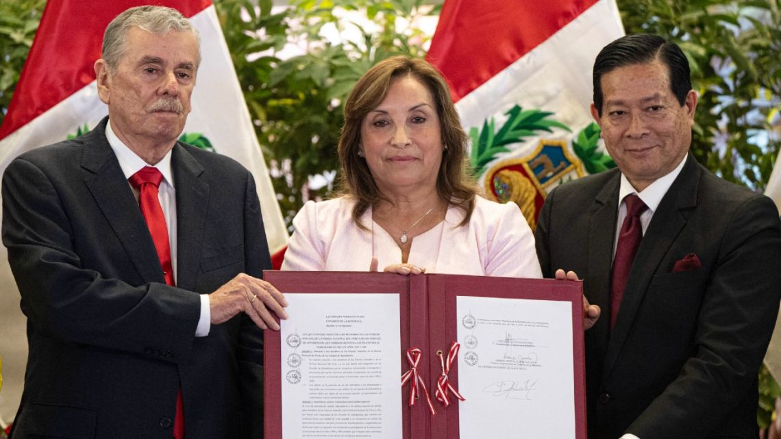 Peru's President Dina Boluarte (C) shows the signed document next to the President of the Cabinet, Eduardo Arana (R), and the Vice President of the Congress, Fernando Rospigliosi (L), during a ceremony enacting an amnesty law for military and police personnel prosecuted for human rights violations at the Government Palace in Lima on August 13, 2025. Peruvian President Dina Boluarte on Wednesday enacted a controversial amnesty law for military and police personnel prosecuted for human rights violations during the armed conflict that ravaged the country between 1980 and 2000. 