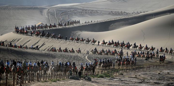 Imagen de turistas visitando el punto escénico de la Montaña Mingsha y el Manantial de la Luna Creciente, en la ciudad de Dunhuang, en la provincia de Gansu, en el noroeste de China.
