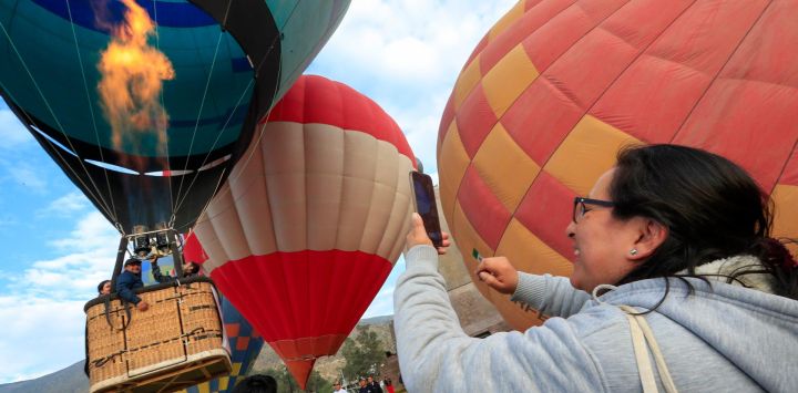 Una mujer graba con un teléfono móvil un globo aerostático mientras se eleva durante el cuarto Festival Internacional del Globo Mitad del Mundo, en la ciudad de Quito, capital de Ecuador.