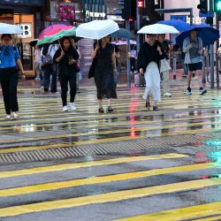 Personas sostienen paraguas mientras caminan por una calle, en Hong Kong, en el sur de China. | Foto:Xinhua/Zhu Wei