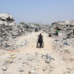 Un niño palestino arrastra una silla de ruedas junto a edificios destruidos en el barrio de Al-Tuffah, en la ciudad de Gaza, tras más de 22 meses de guerra entre Israel y el grupo militante palestino Hamás. | Foto:OMAR AL-QATTAA / AFP