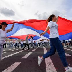 La gente corre con una bandera rusa en la Plaza Dvortsovaya de San Petersburgo, durante el Día de la Bandera Nacional de la Federación Rusa. | Foto:OLGA MALTSEVA / AFP