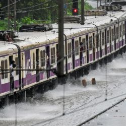 Un tren local circula por una vía férrea inundada durante fuertes lluvias en Mumbai, India. | Foto:PUNIT PARANJPE / AFP