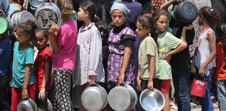 Palestinos se reúnen para recibir comida preparada de un centro de distribución en el campo de refugiados de Nuseirat, en el centro de la Franja de Gaza.