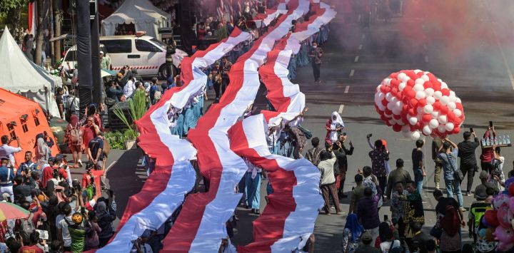 Estudiantes despliegan una bandera larga con los colores nacionales de Indonesia mientras desfilan por las calles durante una ceremonia para conmemorar el Día de la Independencia de Indonesia en Surabaya.