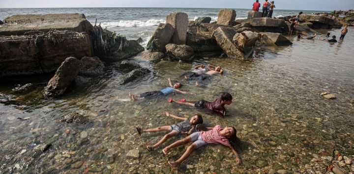 Imagen de niños palestinos desplazados jugando en una playa, en el oeste de la Ciudad de Gaza.