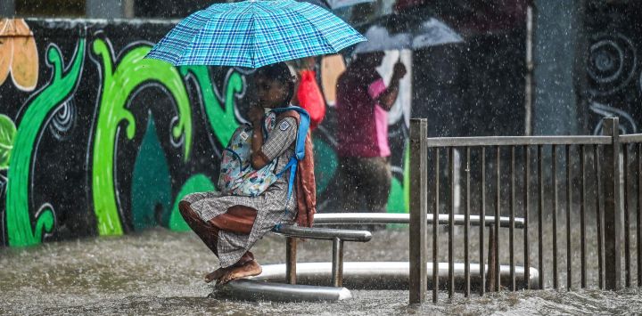Una colegiala sostiene un paraguas mientras está sentada en un banco durante las fuertes lluvias en Mumbai, India.