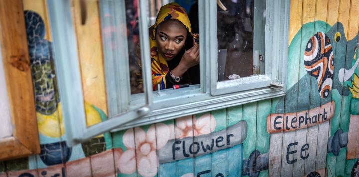 Una participante del concurso Sr. y Sra. Kibera 2025, celebrado para conmemorar el Día Internacional de la Juventud, se mira en un pequeño espejo mientras se maquilla y se arregla en un aula que sirve de zona de bastidores en los terrenos de una iglesia en el asentamiento informal de Kibera, Nairobi.