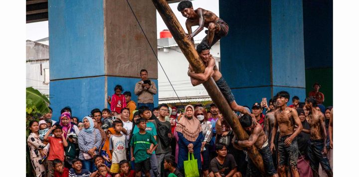 Los participantes trepan por un poste engrasado durante un juego tradicional llamado "Panjat Pinang" para recoger premios colgados en la cima durante las celebraciones del 80.º Día de la Independencia de Indonesia, a orillas del río Kalimalang en Yakarta.