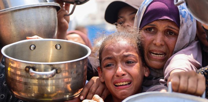 Palestinos se reúnen para recibir comida preparada de un centro de distribución de alimentos en la ciudad de Gaza.