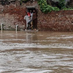 Los aldeanos se encuentran dentro de su casa parcialmente sumergida por las aguas de la inundación después de las fuertes lluvias en la aldea de Bheki Wala, en el distrito de Kasur, en Pakistán. | Foto:Arif Ali / AFP