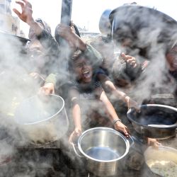 Palestinos extienden ollas vacías frente a un comedor social para recibir arroz cocido, en la ciudad de Gaza. Naciones Unidas declaró oficialmente la hambruna en Gaza el 22 de agosto, culpando a la "obstrucción sistemática" de la ayuda por parte de Israel durante más de 22 meses de guerra. El primer ministro, Benjamin Netanyahu, desestimó rápidamente las conclusiones. | Foto:OMAR AL-QATTAA / AFP