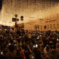 Residentes locales captan el encendido de las luces para conmemorar el Día de la Independencia de Ucrania, en el centro de Járkov, durante la invasión rusa de Ucrania. | Foto:IVAN SAMOILOV / AFP