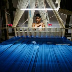Una artesana teje un sari banarasi en un telar manual en un taller de Varanasi, India. El presidente estadounidense, Donald Trump, ha amenazado con duplicar los aranceles de importación a la India del 25 % al 50 % para el 27 de agosto, como castigo por la compra de petróleo a Rusia, alegando que estas compras ayudan a Moscú a financiar su invasión de Ucrania. | Foto:NIHARIKA KULKARNI / AFP
