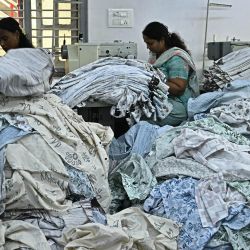 Trabajadores textiles confeccionan ropa en máquinas de coser en una planta de fabricación de prendas de vestir en Bengaluru, India. | Foto:IDREES MOHAMMED / AFP