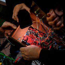 Men repair a disused computer during the 3rd Federal Cyberciruja Meeting in Buenos Aires, on August 16, 2025. Cybercirujas, a collective of Argentine hacktivists, recycle electronic devices to challenge planned obsolescence and the logic of the “computing oligarchy.”