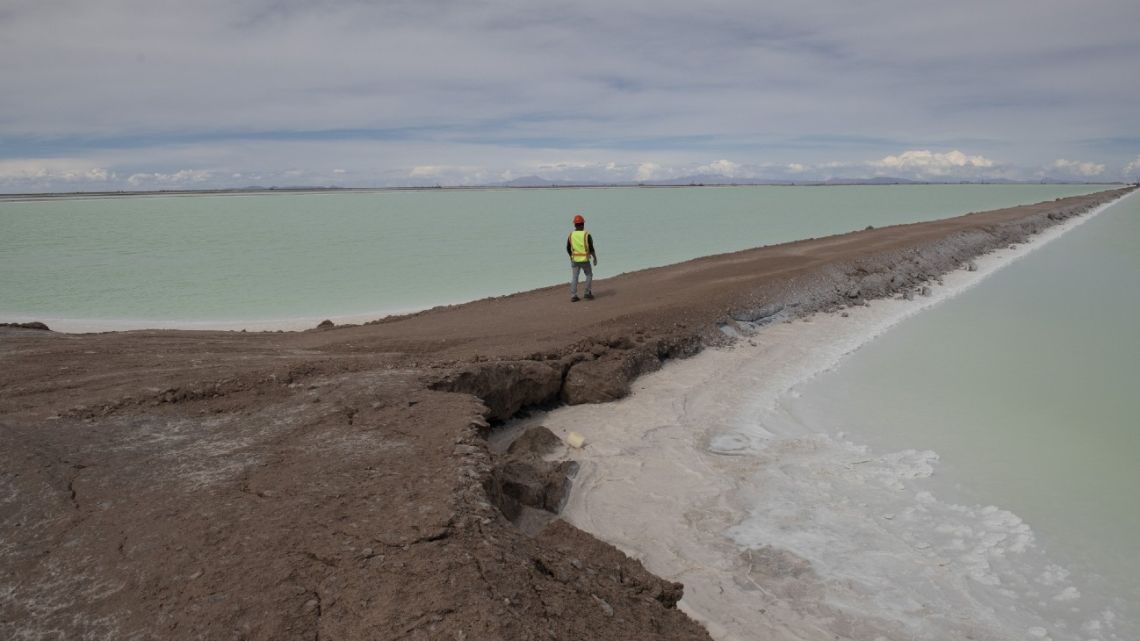 A worker walks between two industrial evaporation pools at a lithium production facility in the Uyuni Salt Flats in Potosí, Bolivia.