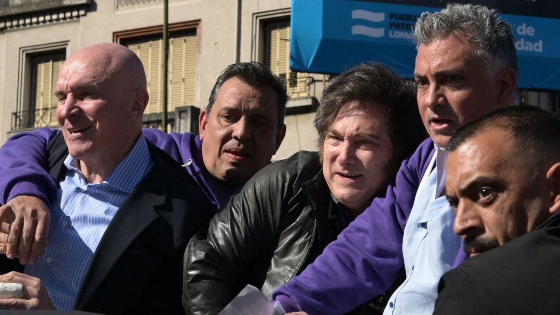 President Javier Milei reacts next to the ruling party's candidate for deputy, José Luis Espert (left), and security personnel as protesters throw objects at them during a motorcade in Lomas de Zamora, Buenos Aires Province, Argentina, on August 27, 2025. 