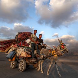 Hombres viajan en una carreta tirada por burros, cargada con una cisterna, colchones, ropa de cama y tiendas de campaña, avanzando por la carretera costera mientras la gente evacua hacia el sur desde la ciudad de Gaza. Israel intensificó su despliegue militar cuando los reservistas comenzaron a responder a las órdenes de reclutamiento antes de una ofensiva planeada sobre la ciudad de Gaza, a pesar de la creciente presión nacional e internacional para poner fin a la campaña de casi dos años en el territorio palestino. | Foto:Eyad Baba / AFP