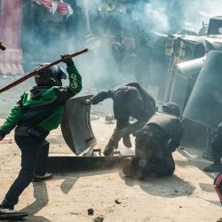 Personas se enfrentaron con miembros del cuerpo de control de disturbios de la Brigada Móvil (Brimob) en medio de una nube de gas lacrimógeno durante una protesta tras la muerte de un mototaxista la noche anterior, frente a la sede de Brimob en Yakarta, indonesia. | Foto:Yasuyoshi Chiba / AFP