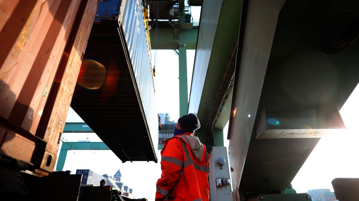 A worker oversees the movement of shipping containers.
