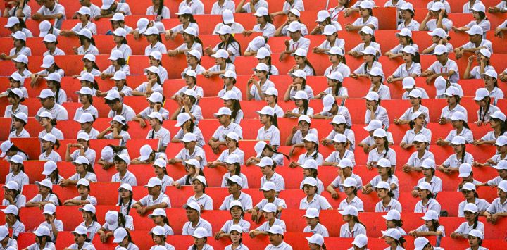 Jóvenes sentados en una tribuna durante un desfile con motivo del 80.º Día Nacional de Vietnam en Hanói.