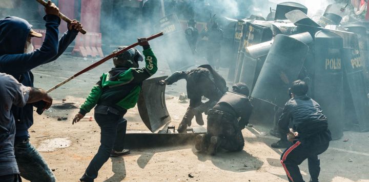 Personas se enfrentaron con miembros del cuerpo de control de disturbios de la Brigada Móvil (Brimob) en medio de una nube de gas lacrimógeno durante una protesta tras la muerte de un mototaxista la noche anterior, frente a la sede de Brimob en Yakarta, indonesia.