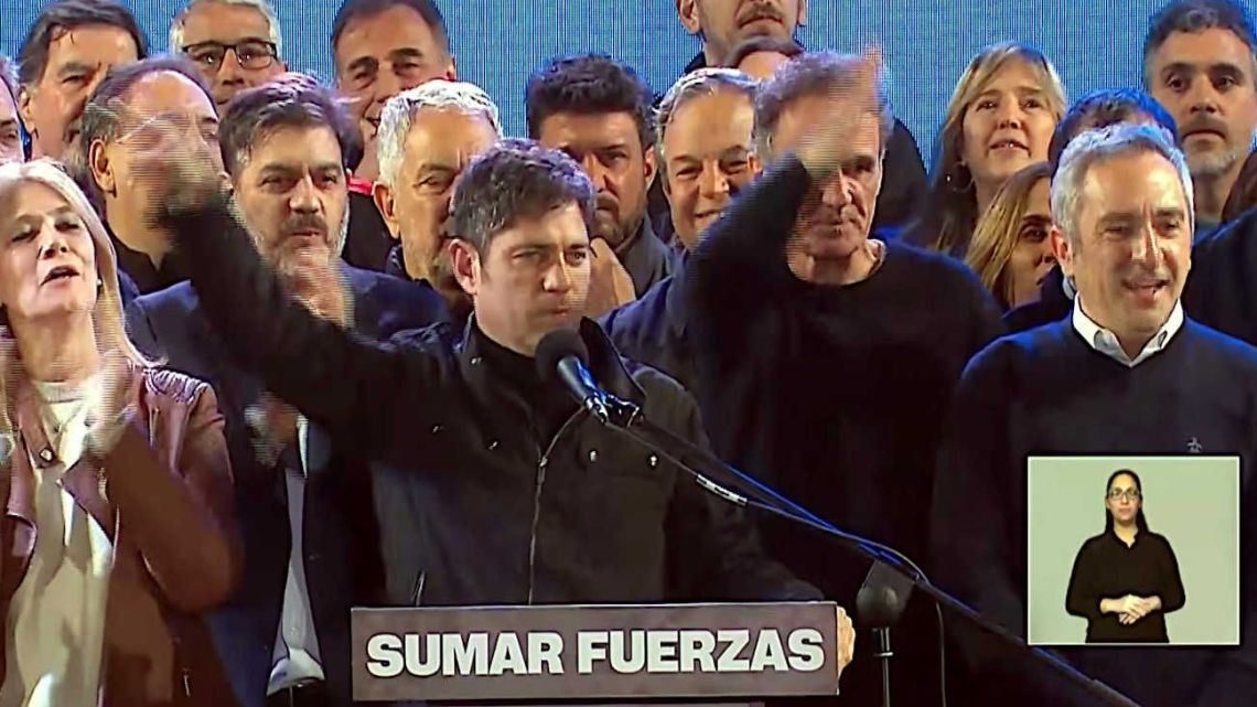 Buenos Aires Province Governor Axel Kicillof celebrates with Peronist leaders onstage.