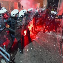 Manifestantes sostienen una valla mientras la policía usa gases lacrimógenos y granadas aturdidoras para dispersar a los manifestantes antigubernamentales frente a la Facultad de Filosofía en la ciudad serbia de Novi Sad, después de que miles de personas se manifestaran exigiendo elecciones anticipadas. | Foto:AFP