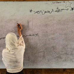 Una maestra de primaria afgana escribe en la pizarra mientras imparte una clase en una escuela de Kandahar. | Foto:Sanaullah Seiam / AFP