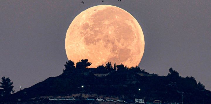 La luna llena se pone detrás del monte Gerizim, como se ve desde Nablus, en la Cisjordania ocupada.