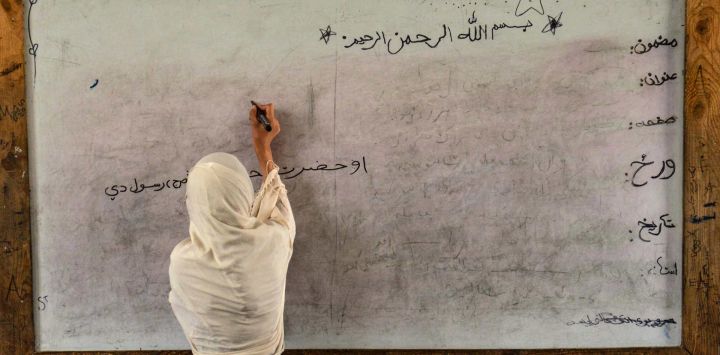 Una maestra de primaria afgana escribe en la pizarra mientras imparte una clase en una escuela de Kandahar.