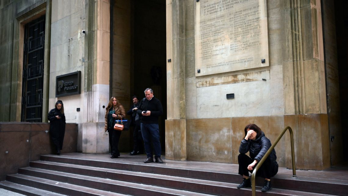 People stand outside a bank in the financial district of Buenos Aires on September 8, 2025