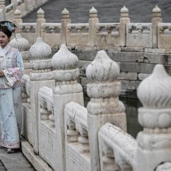 Una mujer vestida con un traje tradicional posa para fotos dentro de la Ciudad Prohibida en Pekín. | Foto:JADE GAO / AFP