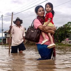 Los residentes caminan por una calle inundada tras las fuertes lluvias monzónicas en Imphal East, en el estado de Manipur, al noreste de la India. | Foto:AFP