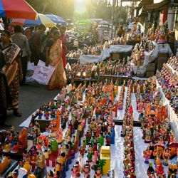 Clientes observan ídolos de deidades hindúes y figuras míticas expuestos a la venta en un puesto antes del festival 'Navaratri' en Chennai, India. | Foto:R. Satish Babu / AFP
