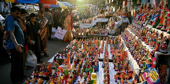 Clientes observan ídolos de deidades hindúes y figuras míticas expuestos a la venta en un puesto antes del festival 'Navaratri' en Chennai, India.