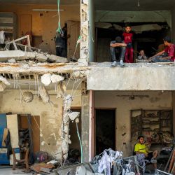 Un hombre y sus hijos se sientan en habitaciones expuestas en un edificio gravemente dañado cerca de la Torre del Soldado Desconocido, destruida por un bombardeo israelí nocturno, en el barrio de Rimal, Ciudad de Gaza. | Foto:OMAR AL-QATTAA / AFP