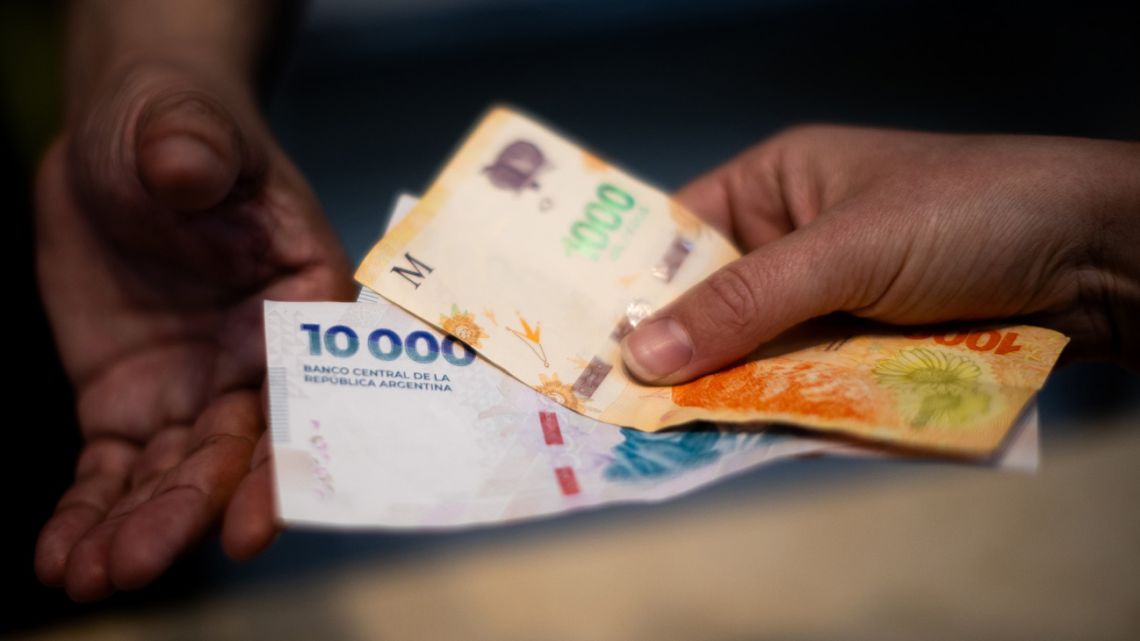 A customer pays with peso banknotes in Buenos Aires.