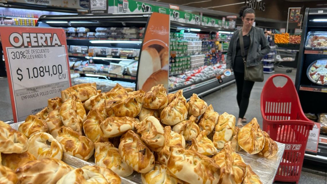 A woman walks past a stand of empanadas on sale at a supermarket in Buenos Aires on September 10, 2025. 