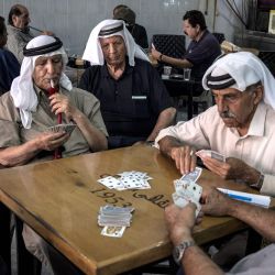Hombres palestinos juegan a las cartas en una cafetería de Ramala, Cisjordania ocupada. | Foto:JOHN WESSELS / AFP