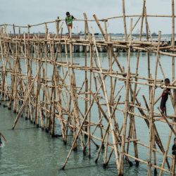 Niños juegan en un puente de bambú improvisado construido para que los trabajadores lo crucen en Cilincing, al norte de Yakarta, Indonesia. | Foto:Yasuyoshi Chiba / AFP