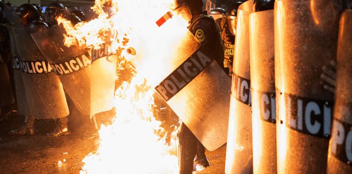 Un agente de la policía antidisturbios es alcanzado por una bomba molotov lanzada por manifestantes durante una manifestación antigubernamental en Lima, Perú.