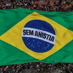 Esta vista aérea muestra a personas portando una enorme bandera brasileña con la leyenda "No a la amnistía" durante una protesta contra una enmienda constitucional conocida como el Proyecto Blindaje, que exige al Congreso autorizar cualquier cargo penal contra diputados y senadores mediante votación secreta, en São Paulo, Brasil. | Foto:NELSON ALMEIDA / AFP