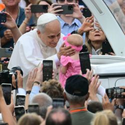 El Papa León XIV bendice a un bebé mientras saluda a la multitud en la plaza de San Pedro durante una audiencia general en el Vaticano. | Foto:Tiziana Fabi / AFP