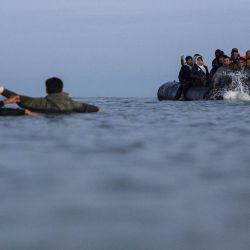 Migrantes intentan subir a un barco de contrabandistas para intentar cruzar el Canal de la Mancha frente a la playa de Gravelines, en el norte de Francia. | Foto:SAMEER Al-DOUMY / AFP