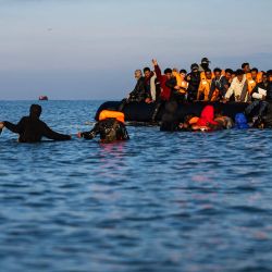 Migrantes se adentran en el mar para intentar abordar las embarcaciones de los traficantes e intentar cruzar el Canal de la Mancha frente a la playa de Gravelines, en el norte de Francia. Dos mujeres murieron durante la noche mientras intentaban cruzar el Canal hacia Gran Bretaña, informaron las autoridades francesas. | Foto:SAMEER Al-DOUMY / AFP