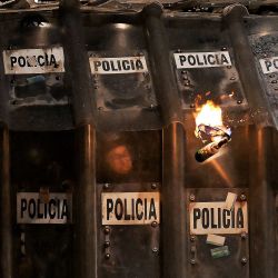 Policías antidisturbios se protegen de bombas molotov durante una protesta por el 11.º aniversario de la desaparición de 43 estudiantes de Ayotzinapa, en la Ciudad de México. En septiembre de 2014, 43 estudiantes de la Escuela Normal Rural de Ayotzinapa desaparecieron tras ser secuestrados en Iguala, Guerrero, México, en lo que se ha calificado como uno de los casos más infames de violación de derechos humanos en México. | Foto:CARL DE SOUZA / AFP
